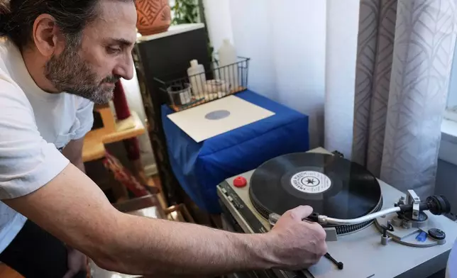 Aadam Jacobs plays a LP (long play) record at his home in Chicago, Thursday, March 19, 2026. (AP Photo/Nam Y. Huh)
