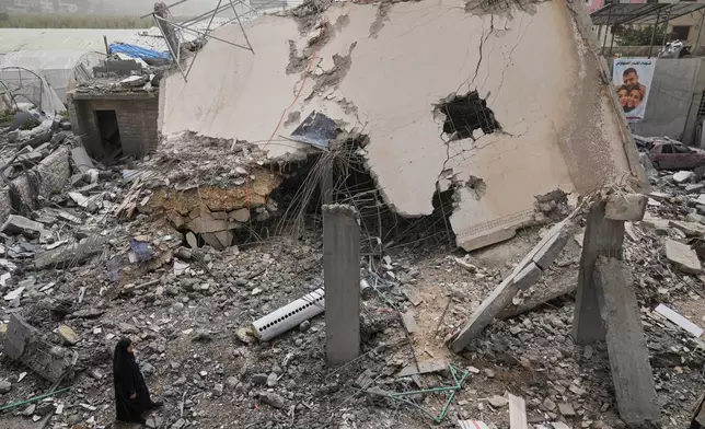 A woman checks a destroyed house that was hit in an Israeli airstrike in Saksakiyeh village, south Lebanon, Friday, April 3, 2026. (AP Photo/Hussein Malla)