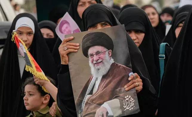 Iraqi women hold a portrait of Iran's late Supreme Leader Ayatollah Ali Khamenei and his son Ayatollah Mojtaba Khamenei, during a protest against U.S. and Israeli attacks on multiple cities across Iran, in the Shi'ite district of Kazimiyah in Baghdad, Iraq, Friday, April 3, 2026. (AP Photo/Hadi Mizban)