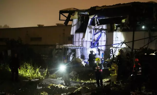 Israeli security forces and rescue teams inspect a site struck by an Iranian missile in Petah Tikva, Israel,Thursday, April 2, 2026. (AP Photo/Ohad Zwigenberg)