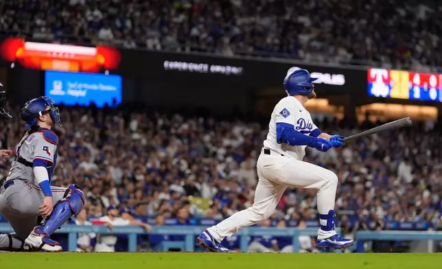 Los Angeles Dodgers' Max Muncy, right, hits a solo home run as Texas Rangers catcher Danny Jansen watches during the fourth inning of a baseball game Friday, April 10, 2026, in Los Angeles. (AP Photo/Mark J. Terrill)