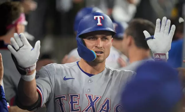 Texas Rangers' Corey Seager is congratulated by teammates in the dugout after hitting a three-run home run during the third inning of a baseball game against the Los Angeles Dodgers, Friday, April 10, 2026, in Los Angeles. (AP Photo/Mark J. Terrill)