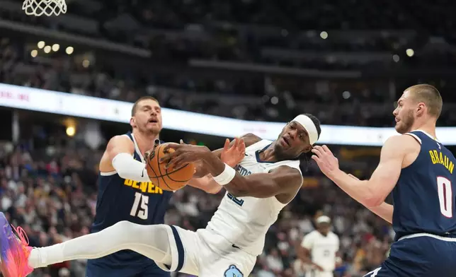 Memphis Grizzlies forward Taylor Hendricks, center, struggles to pull in a loose ball as Denver Nuggets center Nikola Jokić, left, and guard Christian Braun defend in the first half of an NBA basketball game Wednesday, April 8, 2026, in Denver. (AP Photo/David Zalubowski)