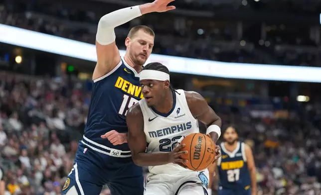 Memphis Grizzlies forward Taylor Hendricks, front, drives to the rim as Denver Nuggets center Nikola Jokić defends in the first half of an NBA basketball game Wednesday, April 8, 2026, in Denver. (AP Photo/David Zalubowski)
