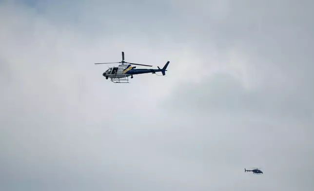 Helicopters fly overhead as law enforcement respond to a shooting at the the Mall of Louisiana, Thursday, April 23, 2026, in Baton Rouge, La. (AP Photo/Matthew Hinton)