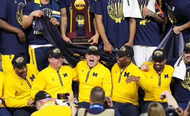 Michigan head coach Dusty May, center, celebrates with his team after defeating UConn in the NCAA college basketball tournament national championship game at the Final Four, Monday, April 6, 2026, in Indianapolis. (AP Photo/AJ Mast)
