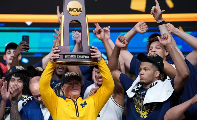 Michigan head coach Dusty May holds the trophy after defeating UConn in the NCAA college basketball tournament national championship game at the Final Four, Monday, April 6, 2026, in Indianapolis. (AP Photo/Abbie Parr)