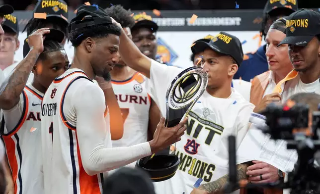 Auburn guard Kevin Overton, left, holds the trophy after he NCAA college basketball NIT Championship game agaisnt Tulsa, Sunday, April 5, 2026, in Indianapolis. (AP Photo/Abbie Parr)