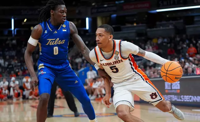 Auburn guard Kaden Magwood (5) drives past Tulsa guard Ade Popoola (0) during the first half of the NCAA college basketball NIT Championship game, Sunday, April 5, 2026, in Indianapolis. (AP Photo/Abbie Parr)