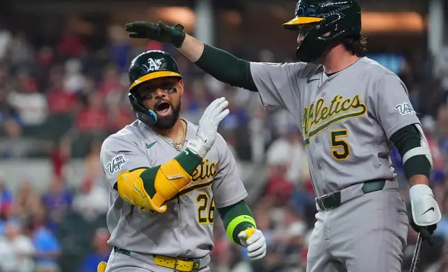 Athletics' Carlos Cortes, left, is greeted by Jacob Wilson after hitting a solo home run off Texas Rangers starting pitcher Nathan Eovaldi during the first inning of a baseball game Friday, April 24, 2026, in Arlington, Texas. (AP Photo/Julio Cortez)