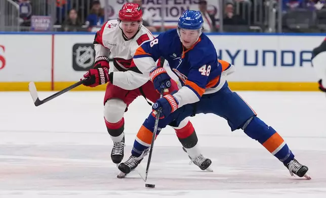 New York Islanders' Matthew Schaefer (48) drives past Carolina Hurricanes' Eric Robinson (50) during the second period of an NHL hockey game Tuesday, April 14, 2026, in Elmont, N.Y. (AP Photo/Frank Franklin II)