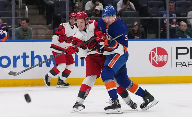 New York Islanders' Adam Pelech (3) checks Carolina Hurricanes' Felix Unger Sorum (36) during the first period of an NHL hockey game Tuesday, April 14, 2026, in Elmont, N.Y. (AP Photo/Frank Franklin II)