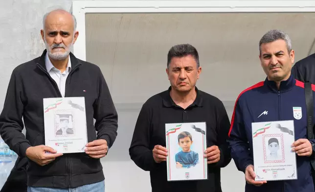 Iran's coach Amir Ghalenoei, center, and Iran's Football Federation Vice President Mehdi Mohammad Nabi, left, hold pictures of children allegedly killed in a U.S. and Israel strikes in Iran, before a friendly soccer match between Iran and Costa Rica, in Antalya, southern Turkey, Tuesday, March 31, 2026. (AP Photo/Riza Ozel)