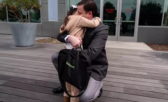 Milenko Faria, whose wife, Dr. Rubeliz Bolivar, is in immigration custody, hugs their daughter, Milena, after his asylum interview at the U.S. Citizenship and Immigration Services facility in Tustin, Calif., Thursday, April 16, 2026. (AP Photo/Jae C. Hong)