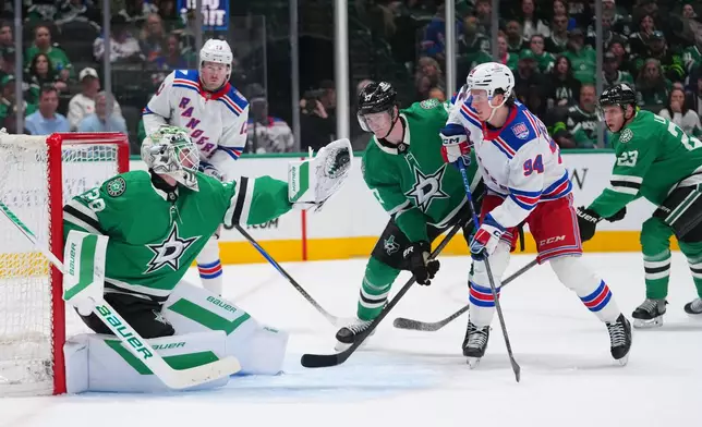Dallas Stars goaltender Jake Oettinger, left, gloves a shot by the New York Rangers during the second period of an NHL hockey game Saturday, April 11, 2026, in Dallas. (AP Photo/Julio Cortez)
