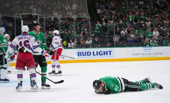 Dallas Stars defenseman Tyler Myers (57) lies on the ice after taking a hit from New York Rangers center Vincent Trocheck (16) during the second period of an NHL hockey game Saturday, April 11, 2026, in Dallas. (AP Photo/Julio Cortez)