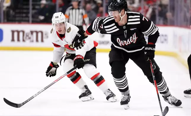 New Jersey Devils defenseman Dougie Hamilton (7) controls the puck past Ottawa Senators defenseman Lassi Thomson (60) during the first period of an NHL hockey game, Sunday, April 12, 2026, in Newark, N.J. (AP Photo/Adam Hunger)