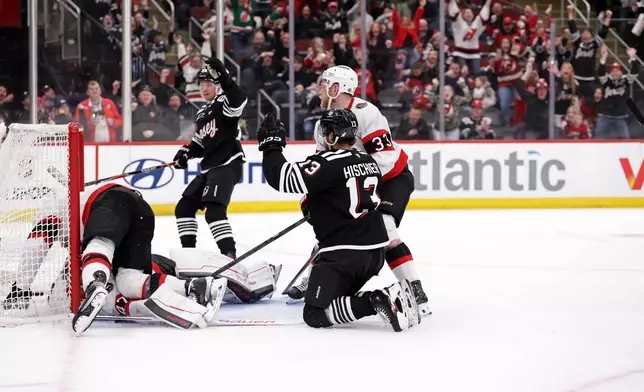 New Jersey Devils center Nico Hischier (13) reacts after scoring the winning goal in front of Ottawa Senators defenseman Nikolas Matinpalo, bottom left, during overtime of an NHL hockey game Sunday, April 12, 2026, in Newark, N.J. (AP Photo/Adam Hunger)
