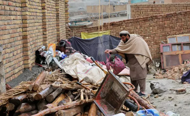 Neighbor Mohibullah Niazi searches through items piled up at a house damaged by an earthquake in the village of Ittefaq, on the outskirts of Kabul, Afghanistan, Saturday, April 4, 2026. (AP Photo/Siddiqullah Alizai)