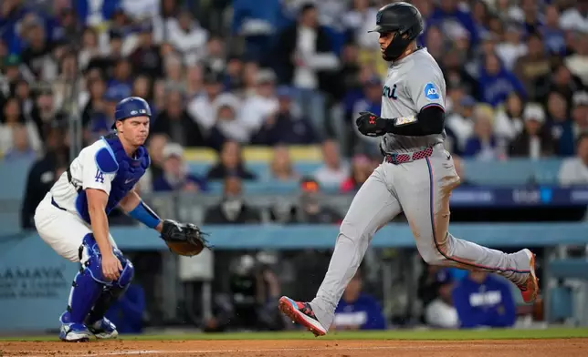 Miami Marlins' Agustin Ramirez, right, scores on a sacrifice fly by Owen Caissie as Los Angeles Dodgers catcher Will Smith watches during the second inning of a baseball game Tuesday, April 28, 2026, in Los Angeles. (AP Photo/Mark J. Terrill)