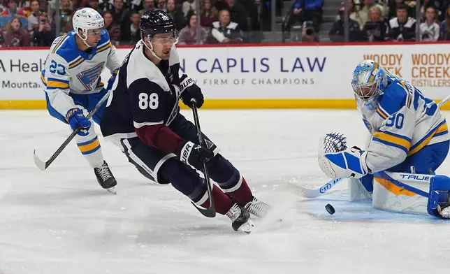 Colorado Avalanche center Martin Necas has his shot blocked by St. Louis Blues goaltender Joel Hofer, right, after drivng past defenseman Logan Mailloux in the first period of an NHL hockey game Sunday, April 5, 2026, in Denver. (AP Photo/David Zalubowski)