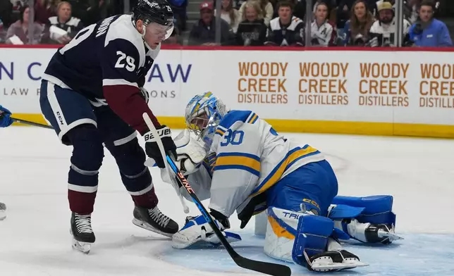 St. Louis Blues goaltender Joel Hofer, right, stops a shot by Colorado Avalanche center Nathan MacKinnon in the first period of an NHL hockey game Sunday, April 5, 2026, in Denver. (AP Photo/David Zalubowski)