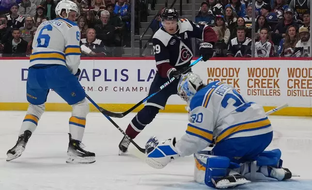 St. Louis Blues goaltender Joel Hofer, right, makes a glove save of a shot by Colorado Avalanche center Nathan MacKinnon as St. Louis defenseman Philip Broberg covers in the first period of an NHL hockey game Sunday, April 5, 2026, in Denver. (AP Photo/David Zalubowski)