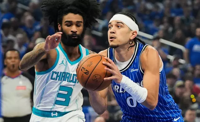 Orlando Magic guard Anthony Black (0) drives around Charlotte Hornets guard Coby White (3) during the first half of an NBA play-in tournament basketball game, Friday, April 17, 2026, in Orlando, Fla. (AP Photo/John Raoux)