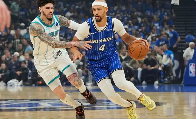 Orlando Magic guard Jalen Suggs (4) drives around Charlotte Hornets guard LaMelo Ball during the first half of an NBA play-in tournament basketball game, Friday, April 17, 2026, in Orlando, Fla. (AP Photo/John Raoux)