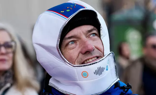 Ottawa city councillor Tim Tierney wears a costume astronaut helmet as he joins others watching the launch of Artemis II on a livestream displayed on the Kipnes Lantern of the National Arts Centre in Ottawa, Ontario, Wednesday, April 1, 2026. (Justin Tang/The Canadian Press via AP)