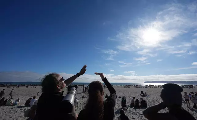 People look up at the sky during a watch party for the return of NASA's Artemis II in Coronado, Calif., Friday, April 10, 2026. (AP Photo/Gregory Bull)
