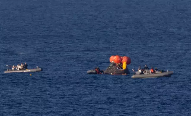 In this photo provided by NASA, recovery teams work to secure the Orion spacecraft carrying Artemis II crewmembers after splashdown in the Pacific Ocean off the coast of California, Friday, April 10, 2026. (Joel Kowsky/NASA via AP)