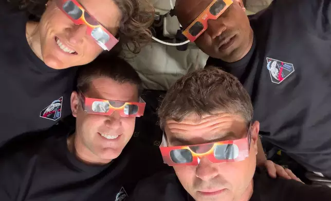 In this image provided by NASA, the Artemis II crew, counterclockwise from top left, Mission Specialist Christina Koch, Mission Specialist Jeremy Hansen, Commander Reid Wiseman, and Pilot Victor Glover pose with eclipse viewers during a lunar flyby, Monday, April 6, 2026. (NASA via AP)