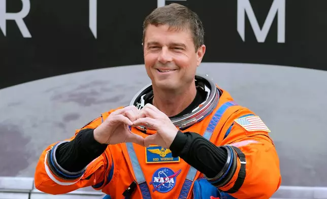 Mission Commander Reid Wiseman makes a heart with his hands as he leaves the Operations and Checkout Building for a trip to Launch Pad 39-B and a planned liftoff on NASA's Artemis II moon rocket at the Kennedy Space Center Wednesday, April 1, 2026, in Cape Canaveral, Fla. (AP Photo/Chris O'Meara)