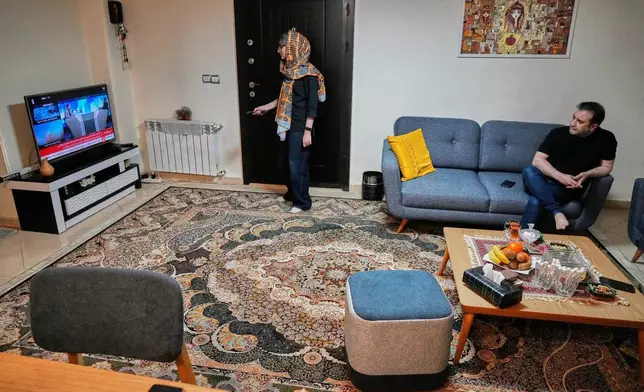 Zahra Arghavan, center, and Mehdi Alishir watch the news on TV in their living room in Tehran, Iran, Sunday, April 5, 2026. (AP Photo/Vahid Salemi)