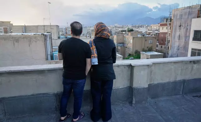 Zahra Arghavan, right, and Mehdi Alishir look out over the city from the rooftop of their apartment in Tehran, Iran, Sunday, April 5, 2026. (AP Photo/Vahid Salemi)