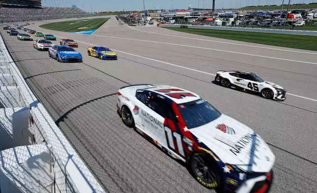 Denny Hamlin (11) and Tyler Reddick (45) lead other drivers into Turn 1 at the start of a NASCAR Cup Series auto race at Kansas Speedway in Kansas City, Kan., Sunday, April 19, 2026. (AP Photo/Colin E. Braley)