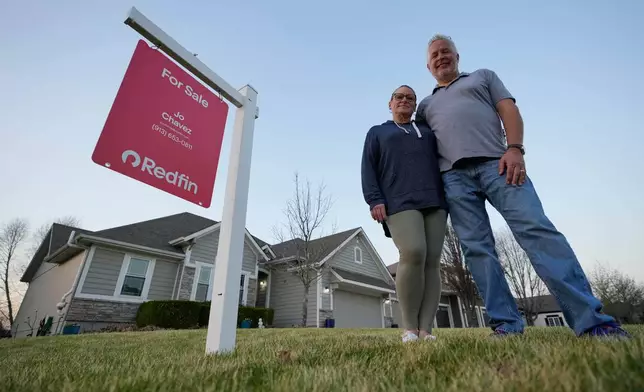Gail and David Sanders stand in front of their home which they have been trying to sell Wednesday, March 25, 2026, in Olathe, Kan. (AP Photo/Charlie Riedel)