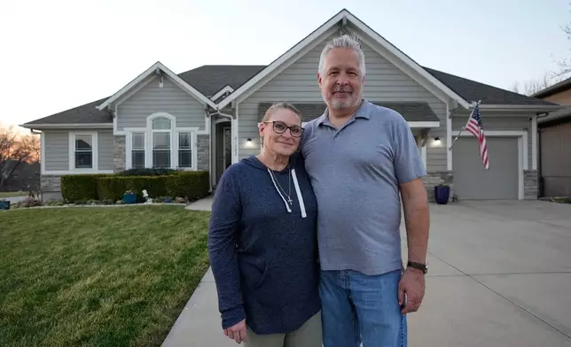 Gail and David Sanders stand in front of their home which they have been trying to sell Wednesday, March 25, 2026, in Olathe, Kan. (AP Photo/Charlie Riedel)