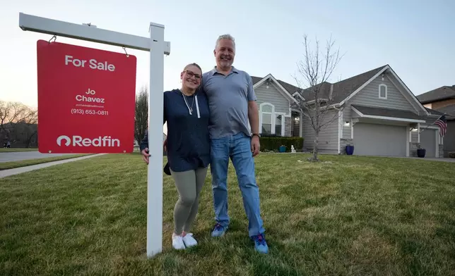 Gail and David Sanders stand in front of their home which they have been trying to sell Wednesday, March 25, 2026, in Olathe, Kan. (AP Photo/Charlie Riedel)