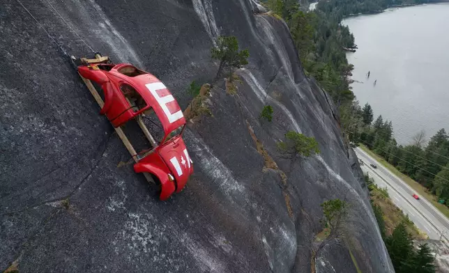 The shell of a Volkswagen Beetle hangs suspended on a cliff above the Sea-to-Sky Highway, in Squamish, British Columbia, Monday, April 6, 2026, after it appeared on the rock face last week with a large "E" on its roof, indicating that University of British Columbia engineering students carried out a long-standing tradition of placing the shell in difficult to reach locations. (Darryl Dyck/The Canadian Press via AP)