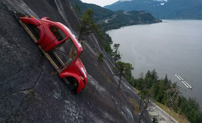 The shell of a Volkswagen Beetle hangs suspended on a cliff above the Sea-to-Sky Highway, in Squamish, British Columbia, Monday, April 6, 2026, after it appeared on the rock face last week with a large "E" on its roof, indicating that University of British Columbia engineering students carried out a long-standing tradition of placing the shell in difficult to reach locations. (Darryl Dyck/The Canadian Press via AP)