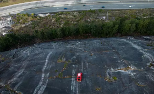 The shell of a Volkswagen Beetle hangs suspended on a cliff above the Sea-to-Sky Highway, in Squamish, British Columbia, Monday, April 6, 2026, after it appeared on the rock face last week with a large "E" on its roof, indicating that University of British Columbia engineering students carried out a long-standing tradition of placing the shell in difficult to reach locations. (Darryl Dyck/The Canadian Press via AP)