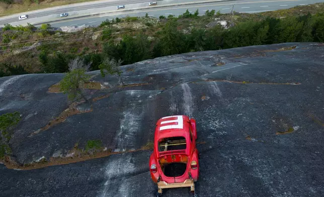 The shell of a Volkswagen Beetle hangs suspended on a cliff above the Sea-to-Sky Highway, in Squamish, British Columbia, Monday, April 6, 2026, after it appeared on the rock face last week with a large "E" on its roof, indicating that University of British Columbia engineering students carried out a long-standing tradition of placing the shell in difficult to reach locations. (Darryl Dyck/The Canadian Press via AP)