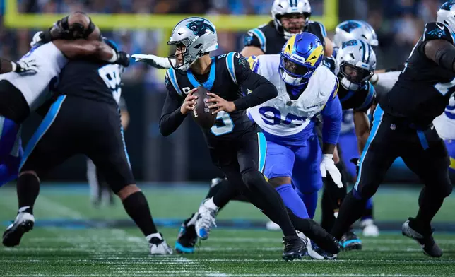 FILE - Carolina Panthers quarterback Bryce Young (9) scrambles to his left to avoid Los Angeles Rams defensive tackle Poona Ford (95) during an NFL wild card playoff football game, Jan. 10, 2026, in Charlotte, N.C. (AP Photo/Brian Westerholt, File)