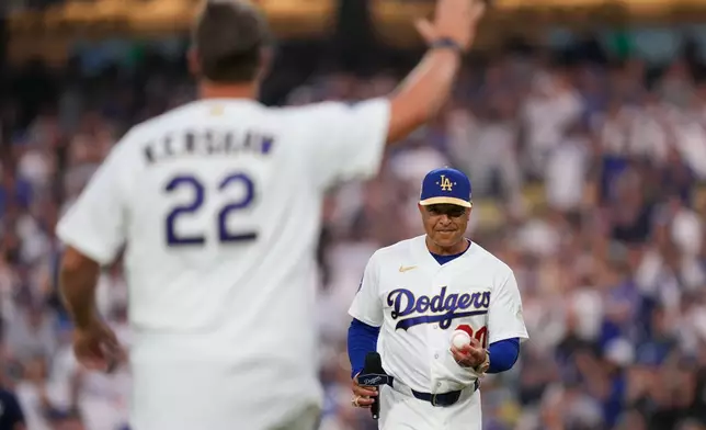 FILE - Former Los Angeles Dodgers pitcher Clayton Kershaw, left, waves as manager Dave Roberts waits before throwing out the ceremonial first pitch and receiving his ring during a World Series ring ceremony prior to a baseball game against the Arizona Diamondbacks, Friday, March 27, 2026, in Los Angeles. (AP Photo/Mark J. Terrill, File)