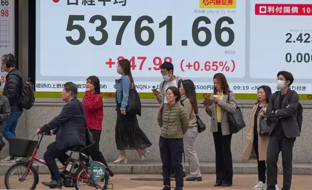 People stand in front of an electronic stock board showing Japan's Nikkei index at a securities firm Tuesday, April 7, 2026, in Tokyo. (AP Photo/Eugene Hoshiko)