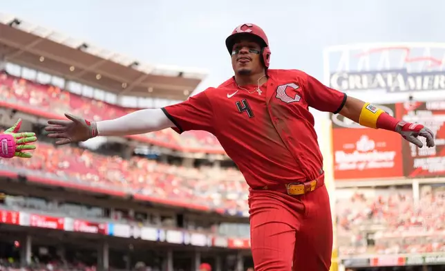 Cincinnati Reds' Noelvi Marte reaches for Elly de la Cruz's hand to celebrate after scoring on a wild pitch by Los Angeles Angels pitcher Chase Silseth during the eighth inning of a baseball in Cincinnati, Saturday, April 11, 2026. (AP Photo/Carolyn Kaster)