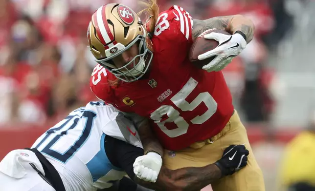 FILE - San Francisco 49ers tight end George Kittle (85) breaks a tackle by Tennessee Titans safety Kendell Brooks, left, during the first half of an NFL football game, Sunday, Dec. 14, 2025, in Santa Clara, Calif. (AP Photo/Jed Jacobsohn, File)