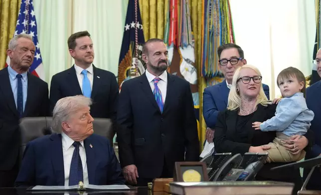 Sierra Smith holds her son Travis, 2, during an event on health care affordability with President Donald Trump, and others, in the Oval Office at the White House, Thursday, April 23, 2026, in Washington. (AP Photo/Mark Schiefelbein)